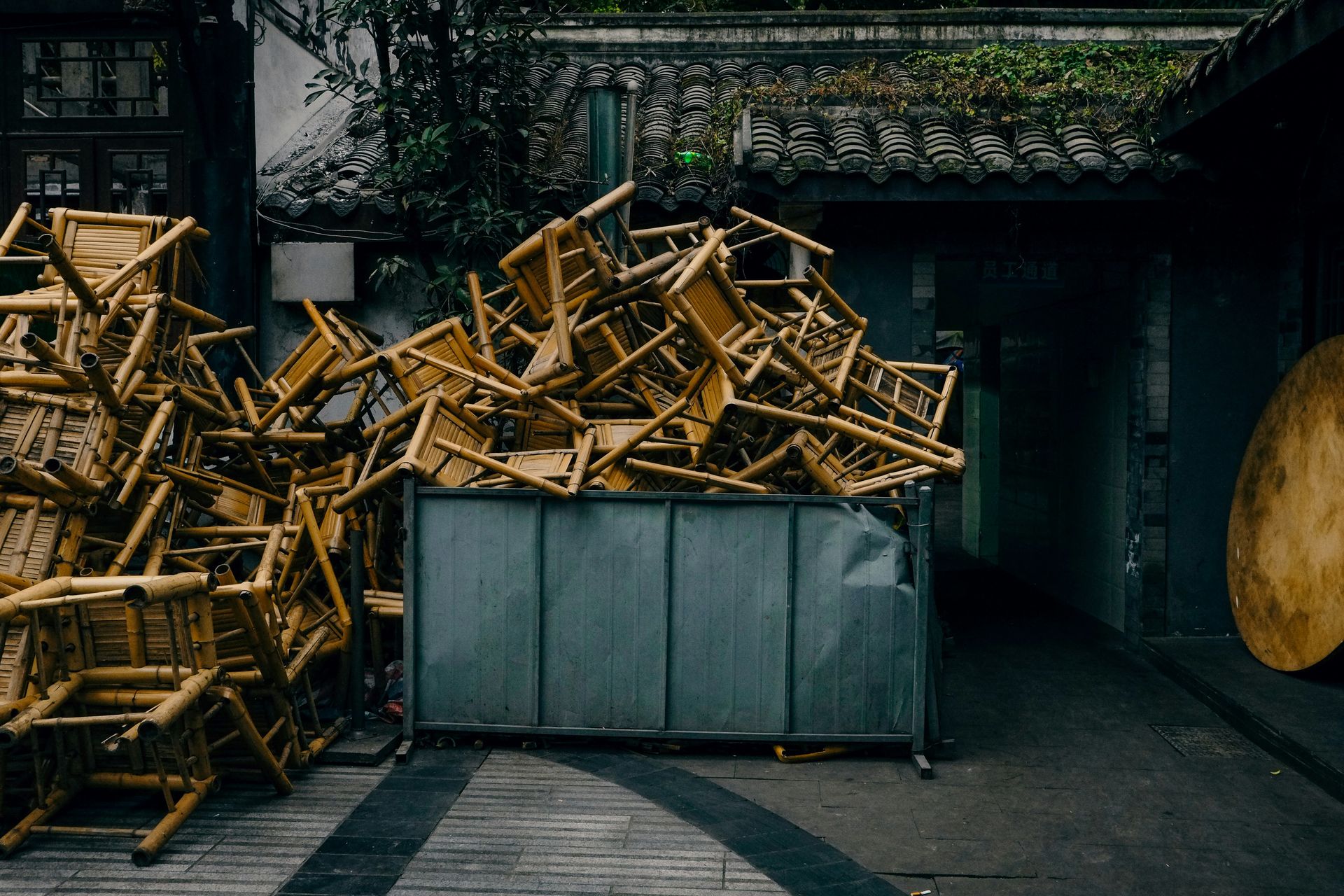 Chairs piled high in a metal container.
